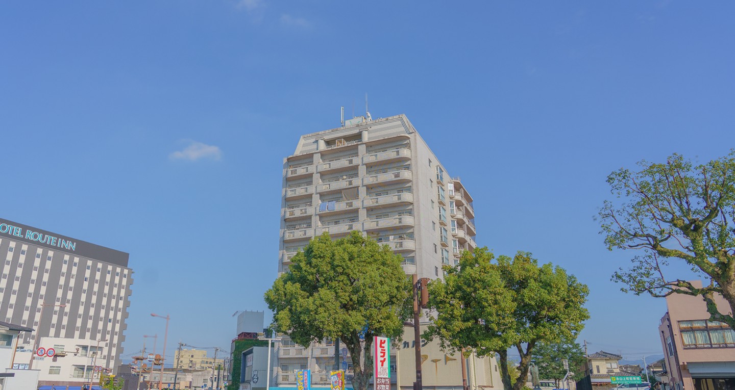 青空の下、街路樹と建物が並ぶ都城の街並み