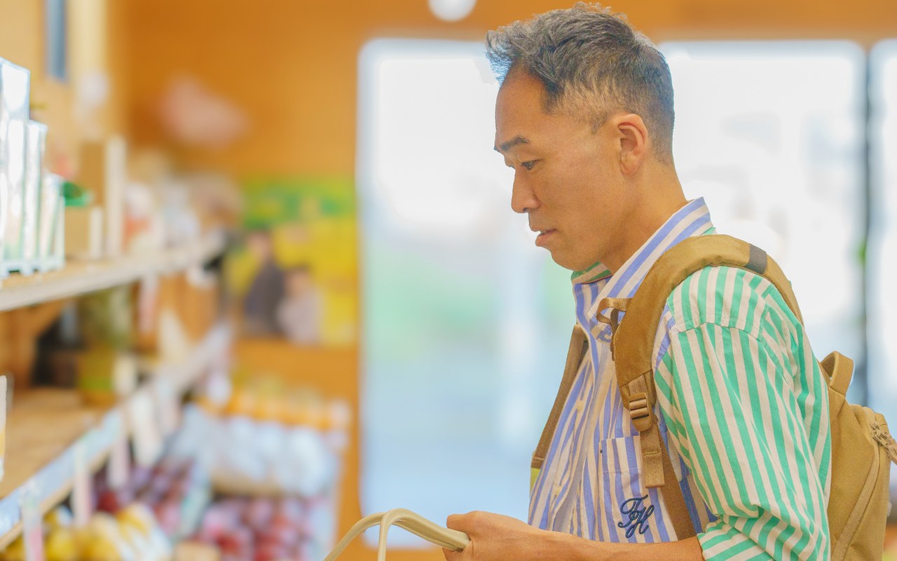 リュックを背負い、店内の商品棚を見ながら買い物をするRyujiさん